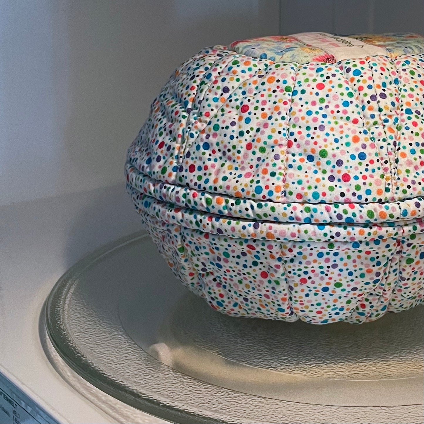 Microwavable bowl cozy in multicolored dots design with bowl cozy lid viewed in microwave.
