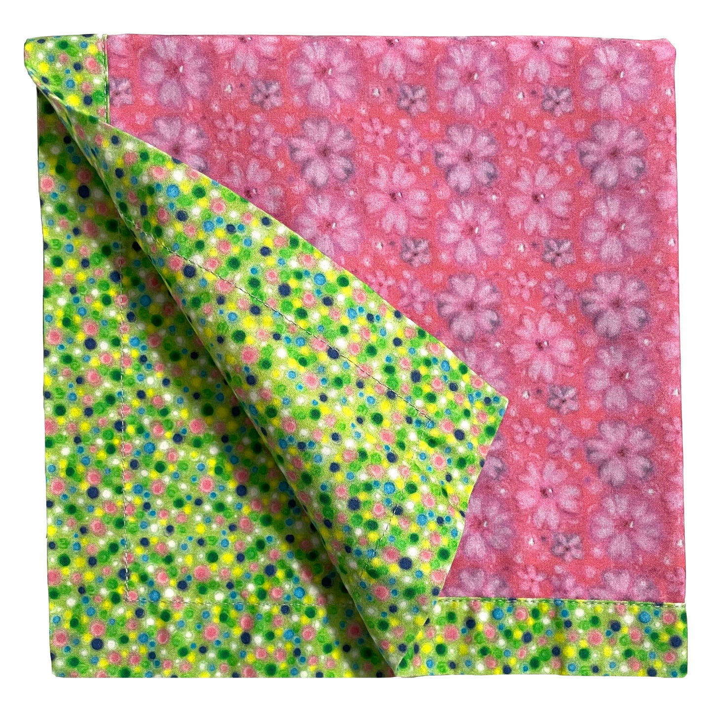 2-color reversible cloth napkin quarter-folded showing back green polka dots design and front pink dog roses design with green polka dots border.
