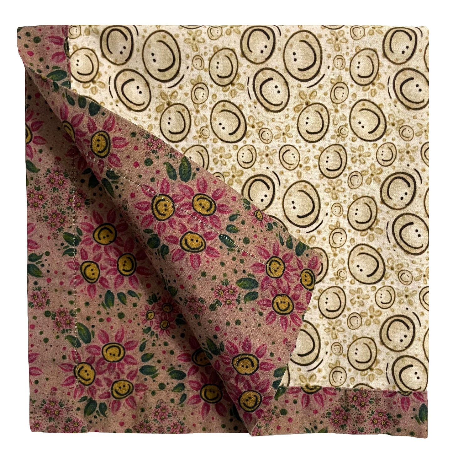 2-color reversible cloth napkin quarter-folded showing back gold-rose smiley floral design and front natural tone smileys design with rose-gold smiley floral border.