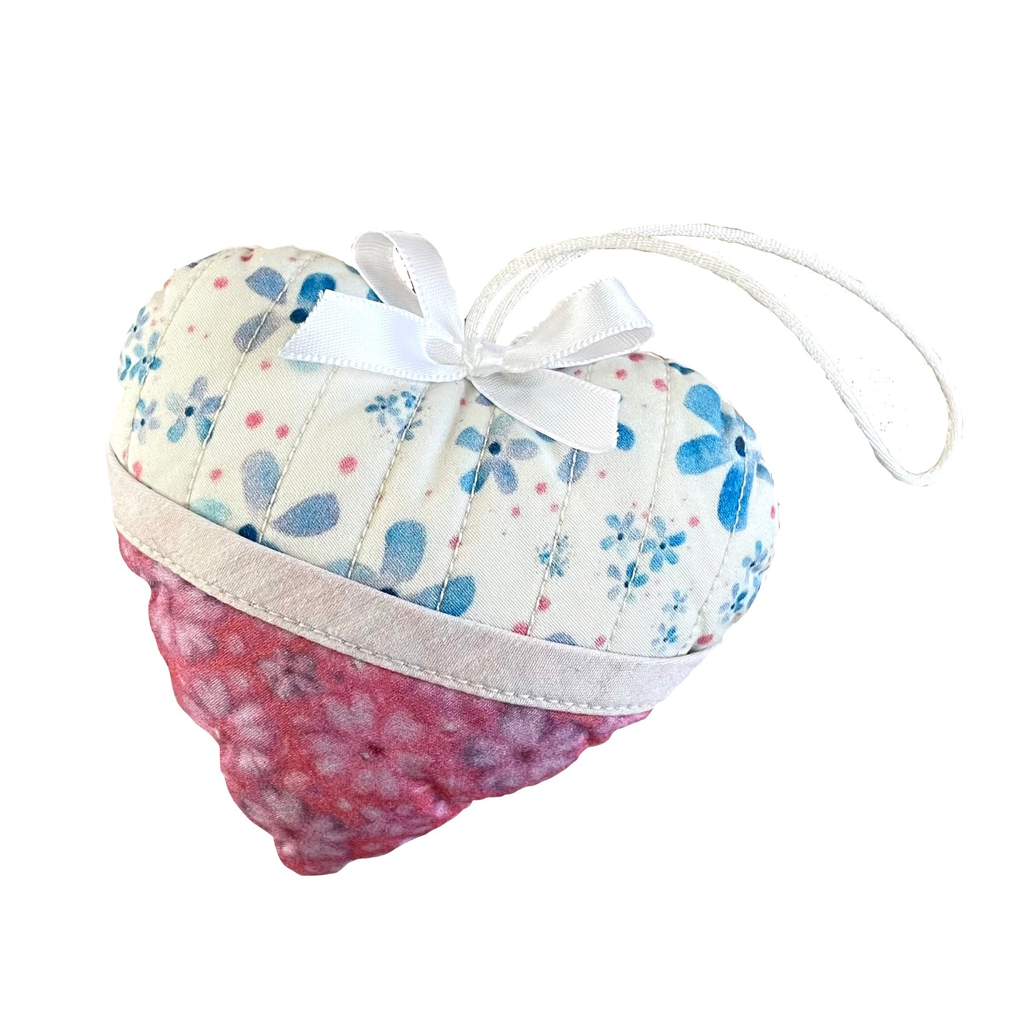 Heart-shaped quilted and stuffed ornament in blue, white, pink floral designs with hemmed pocket and white satin cord and bow.