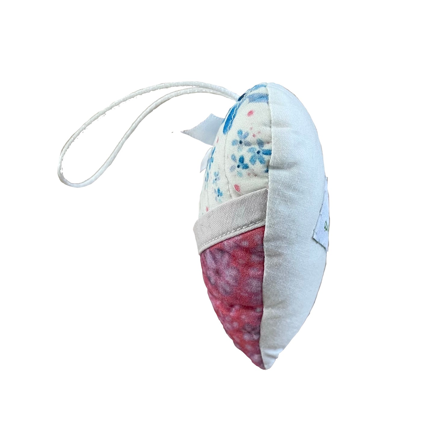Side view of heart-shaped quilted and stuffed ornament in blue, white, pink floral designs with hemmed pocket and white satin cord and bow.