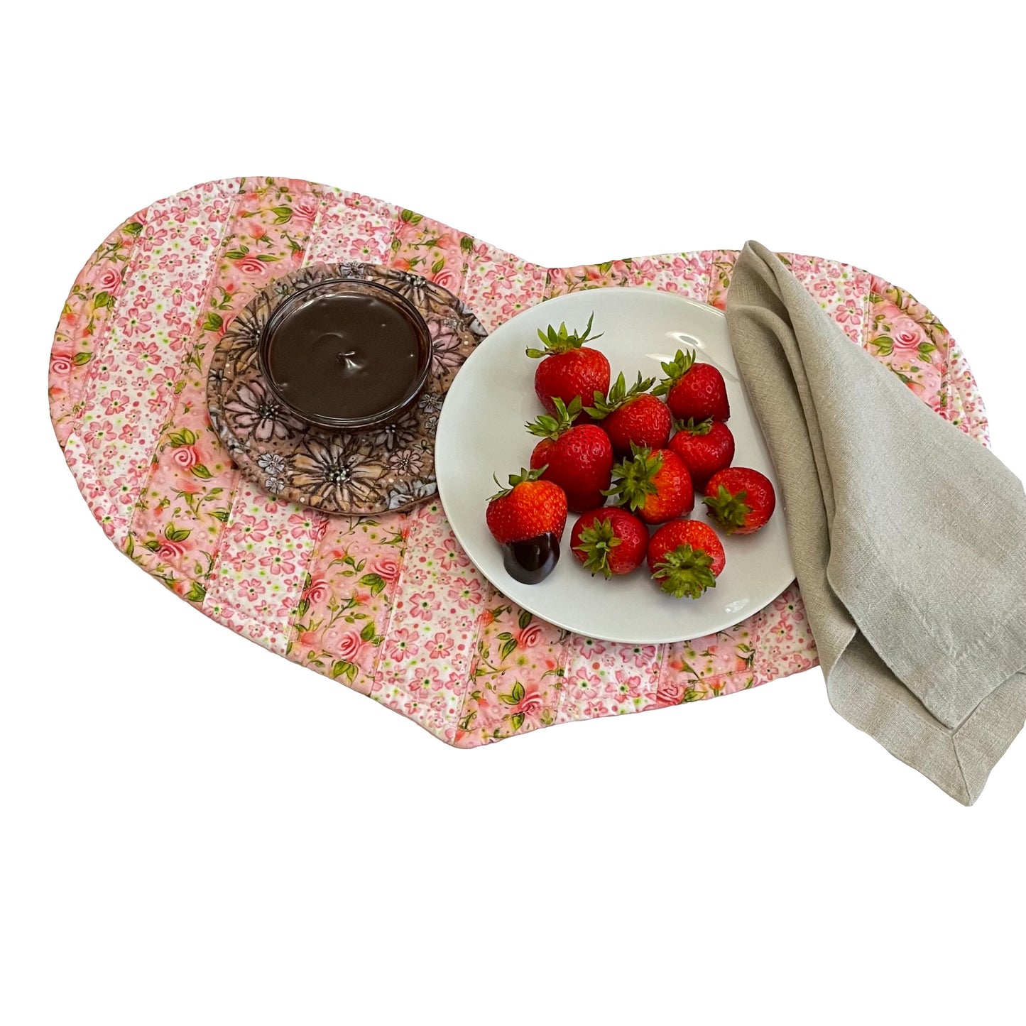 Quilted heart shaped placemats with pink floral stripes and place setting of strawberries and chocolate dipping sauce.