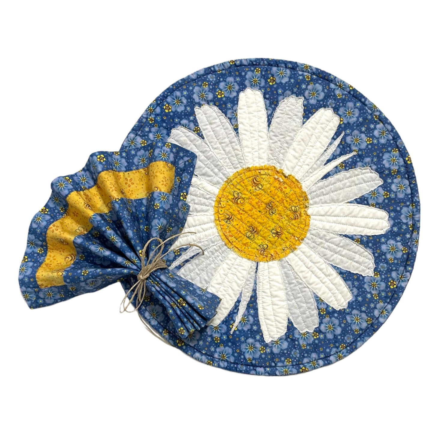 Quilted placemat round daisy on blue background with cotton cloth napkin on top in matching colors, blue and yellow, fan-folded.